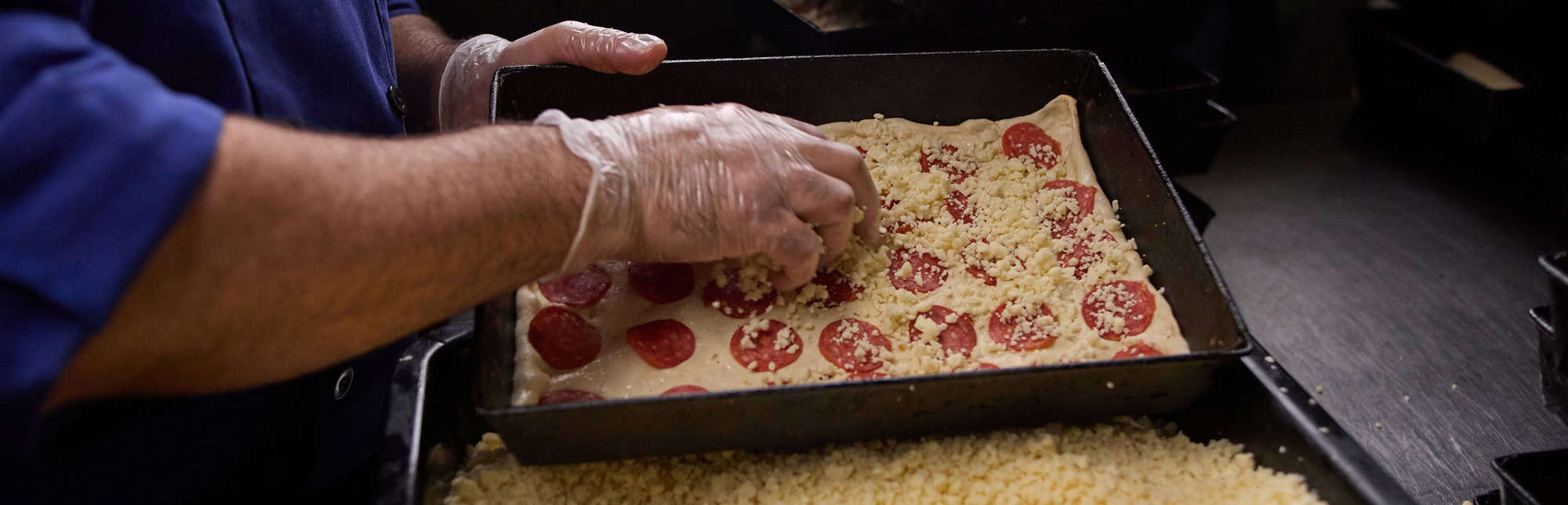 Freshly made pizza with pepperoni and cheese being prepared for baking at Buddy's Pizza.